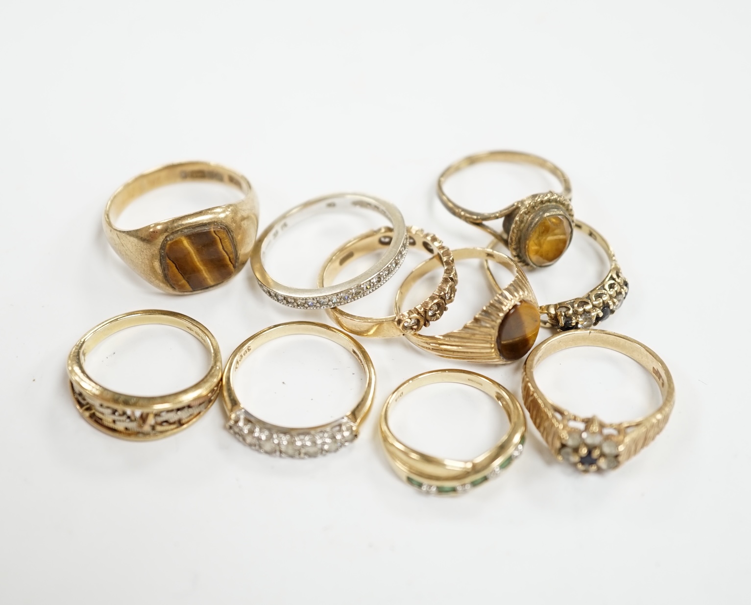 Ten assorted modern 9ct gold and mainly gem set rings, including two with tiger's eye quartz and a seven stone half hoop diamond set, size M/N, gross weight 25.5 grams. Condition - fair